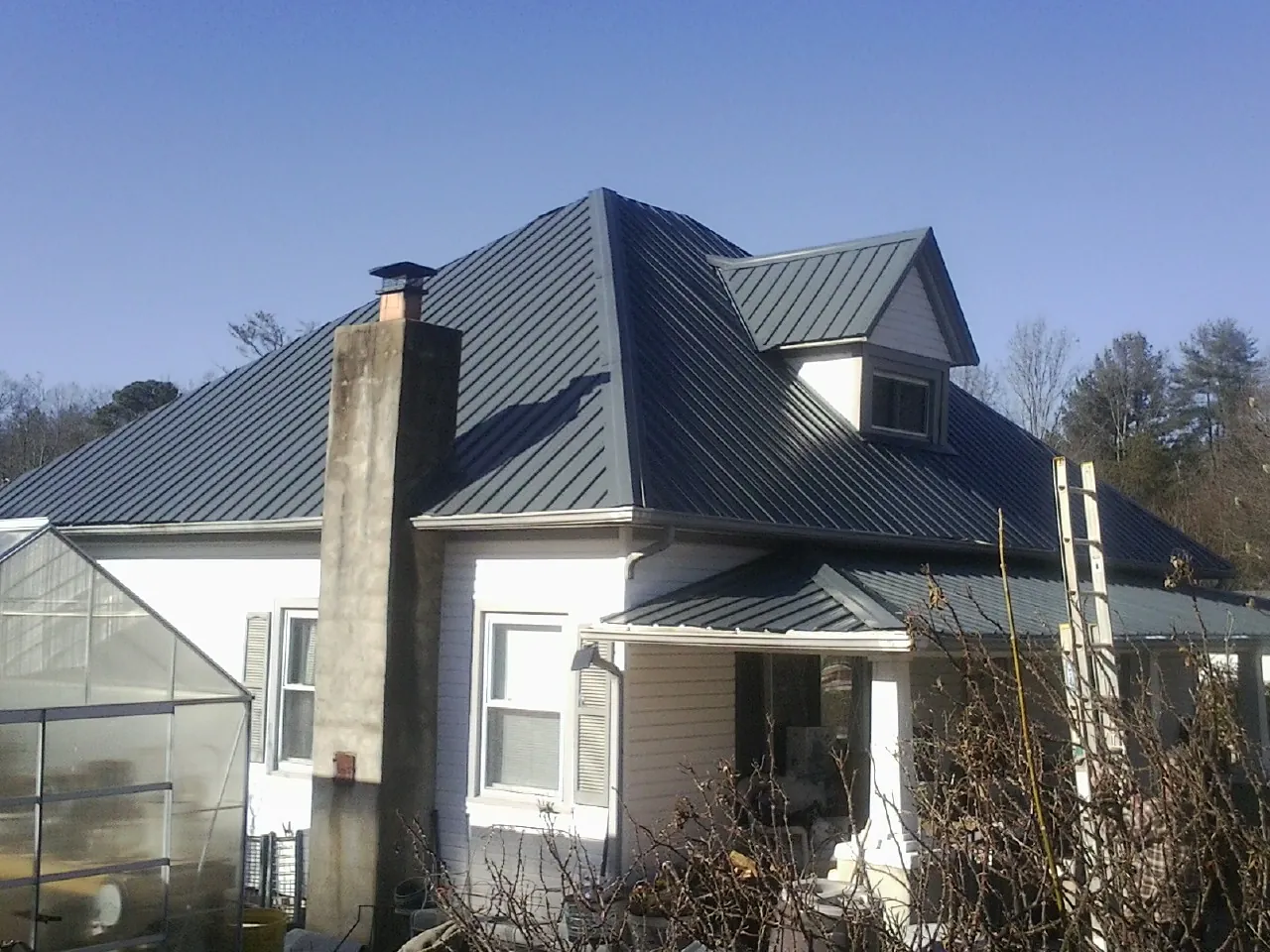 Dark blue standing seam metal roof on a white farmhouse with dormer — Slate & Tile Roof Repair by Roofing Brothers in Cape May Point