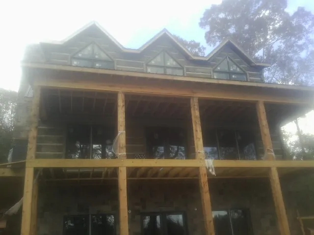 Dormers and porch framing on a large log home under construction — Roof Coating work by our crew in Cape May Point