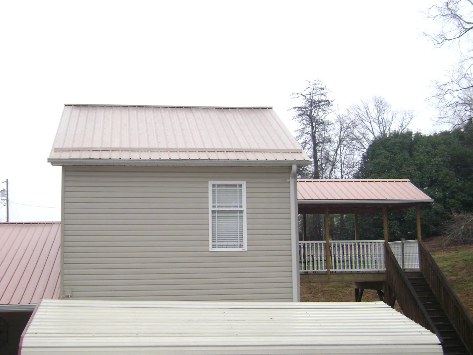 Tan metal roofs on a two story addition and attached porch, from a Roof Replacement job in Cape May Point