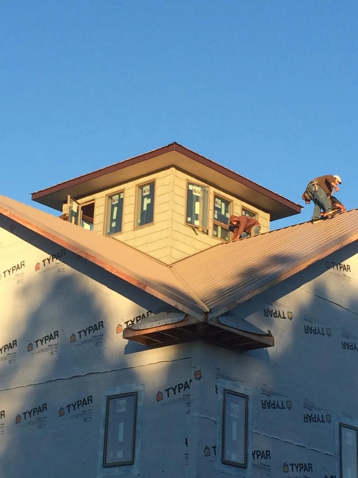 Roofers working around a rooftop cupola on a new metal roof at sunset — Roof Waterproofing in Cape May Point by Roofing Brothers